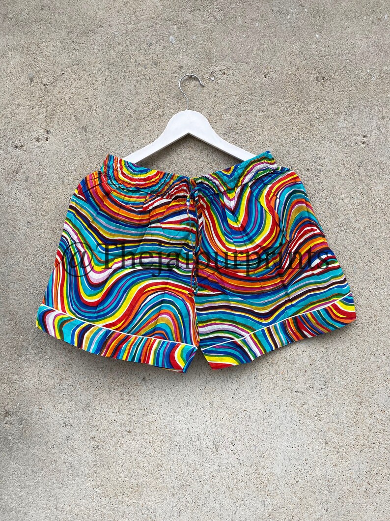 May include: Colorful patterned shorts with a white elastic waistband and a white trim around the edges. The shorts have a wavy, abstract design in shades of blue, red, yellow, orange, and green.