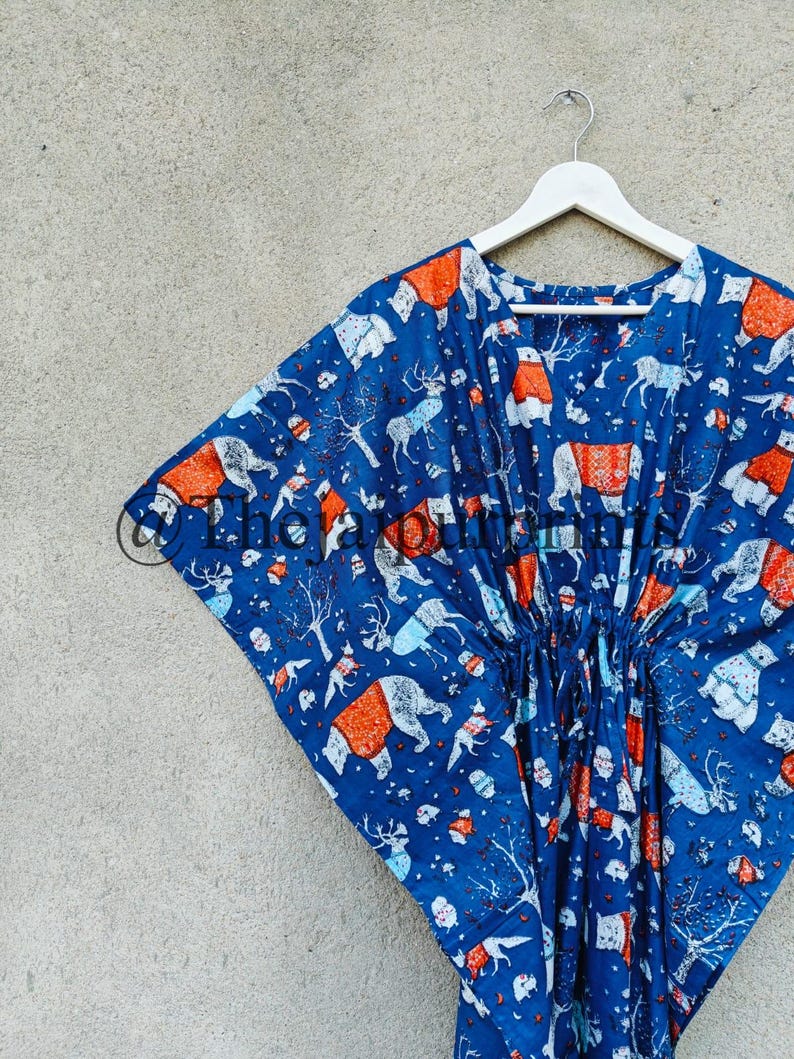 May include: A blue and orange kaftan with a winter animal print. The kaftan has a drawstring waist and is hanging on a white hanger.