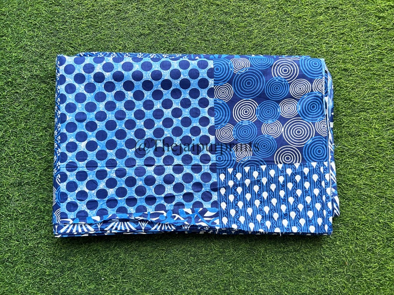 以下が含まれることがあります： 青と白の綿生地で、パッチワークのデザインになっています。生地には、水玉模様、同心円模様、繰り返し涙模様の3つの異なるパターンがあります。