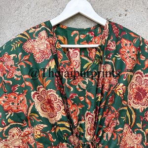May include: A green cotton kaftan with a floral print in shades of red, orange, and yellow. The kaftan has a V-neck and a drawstring waist. The text "@TheJaipurPrints" is visible on the fabric.