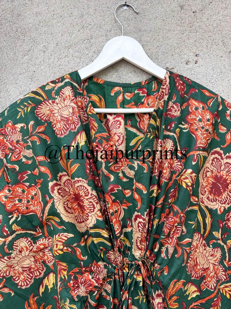 May include: A green cotton kaftan with a floral print in shades of red, orange, and yellow. The kaftan has a V-neck and a drawstring waist. The text "@TheJaipurPrints" is visible on the fabric.