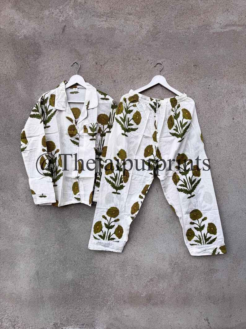 May include: White pajama set with a green floral pattern. The set includes a button-down shirt and matching pants, both hanging on white hangers. The text "The favour prints" is visible on the shirt.