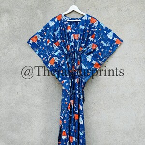 May include: A blue kaftan with a white and orange print of animals. The kaftan has a drawstring waist and is hanging on a white hanger.