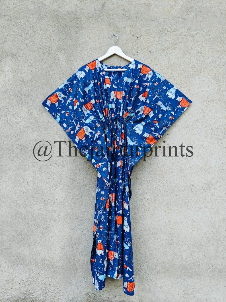 May include: A blue kaftan with a white and orange print of animals. The kaftan has a drawstring waist and is hanging on a white hanger.