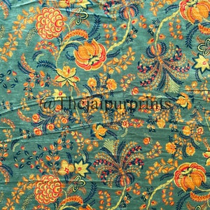 May include: A green fabric with a floral pattern. The flowers are orange, yellow, and red. The fabric has a vintage look.