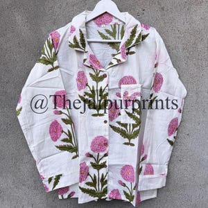 May include: White button-down shirt with a floral print in pink and green. The shirt features a classic collar, long sleeves, and a pocket on the chest. The text "@thejaipurprints" is printed on the shirt.