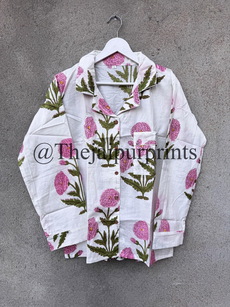 May include: White button-down shirt with a floral print in pink and green. The shirt features a classic collar, long sleeves, and a pocket on the chest. The text "@thejaipurprints" is printed on the shirt.