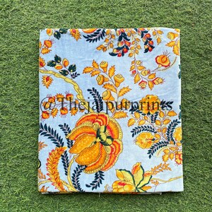 May include: A light blue fabric with a floral pattern in shades of yellow, orange, and green. The fabric has a vintage feel and is perfect for crafting projects.
