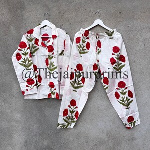 May include: White pajama set with a red floral pattern. The set includes a button-down shirt and drawstring pants. The floral design features red flowers and green leaves. The text "@Thejaipurprints" is visible on the shirt.