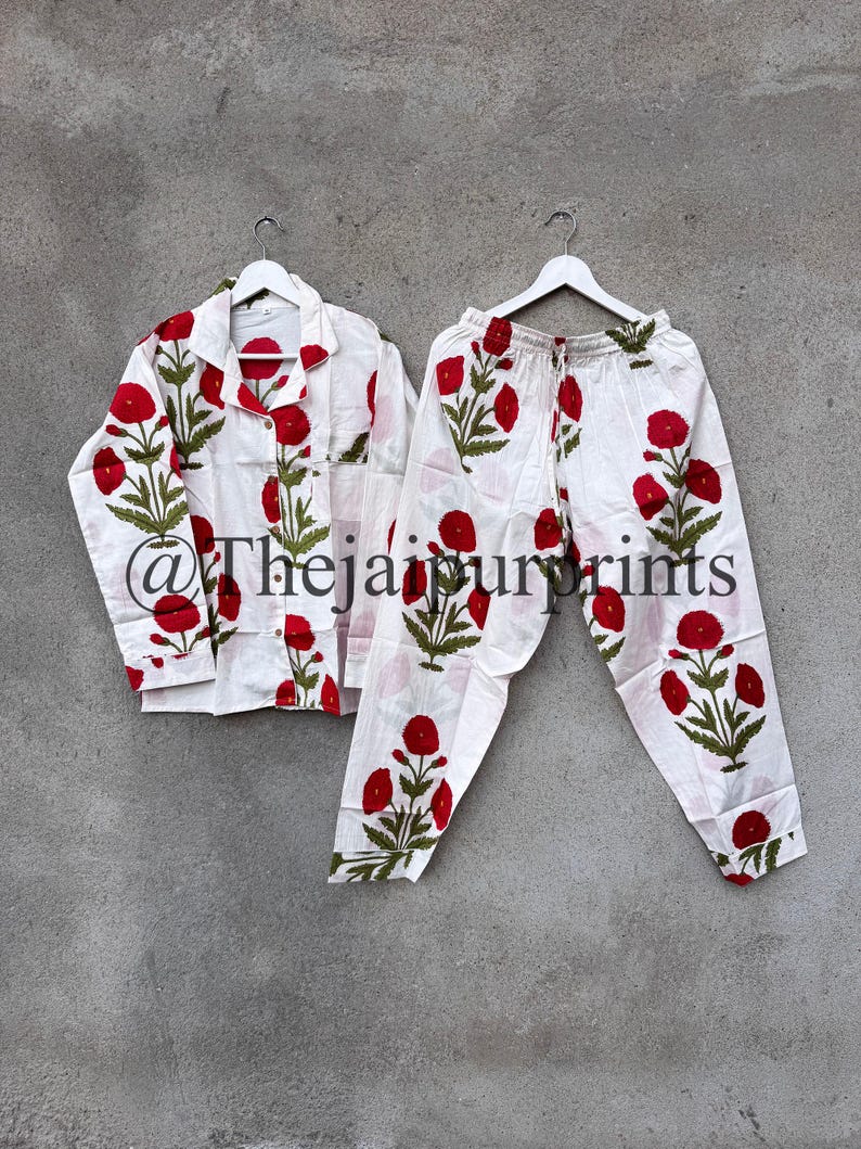 May include: White pajama set with a red floral pattern. The set includes a button-down shirt and drawstring pants. The floral design features red flowers and green leaves. The text "@Thejaipurprints" is visible on the shirt.