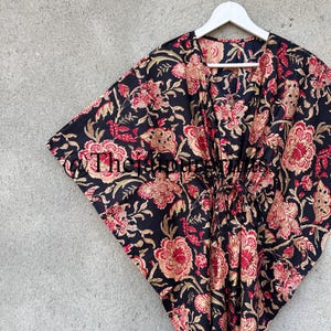May include: Black floral print kaftan with a V-neck and a tie at the waist.