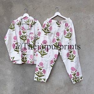 May include: White pajama set with a pink floral pattern and green leaves. The set includes a button-down shirt with a chest pocket and matching pants. The text "@Thejaipurprints" is visible on the bottom of the image.