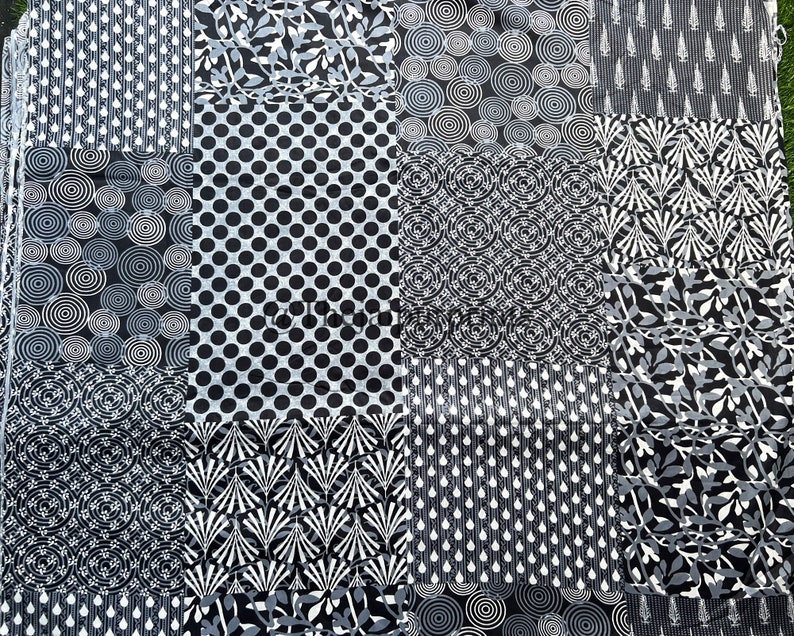 以下が含まれることがあります： 黒と白のパッチワークデザインの布。布には、円、ドット、葉など、さまざまな幾何学模様が施されています。