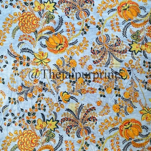 May include: A blue fabric with a floral pattern in shades of yellow, orange, and green. The flowers are stylized and have a vintage feel.