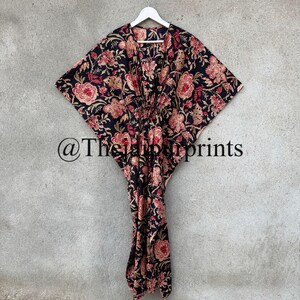 May include: A black and floral print kaftan with a V-neckline and a tie at the waist. The kaftan has a long, flowing silhouette and is perfect for a relaxed, bohemian look. @TheHappyPrints