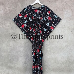 May include: A black kaftan with a white hanger. The kaftan has a red and blue print of polar bears wearing red hats and scarves. The print also includes trees and other wintery elements. The kaftan has a drawstring at the waist.