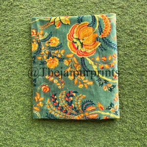 May include: A green fabric with a floral pattern in shades of yellow, orange, and red. The fabric has a vintage feel and is perfect for crafting projects.