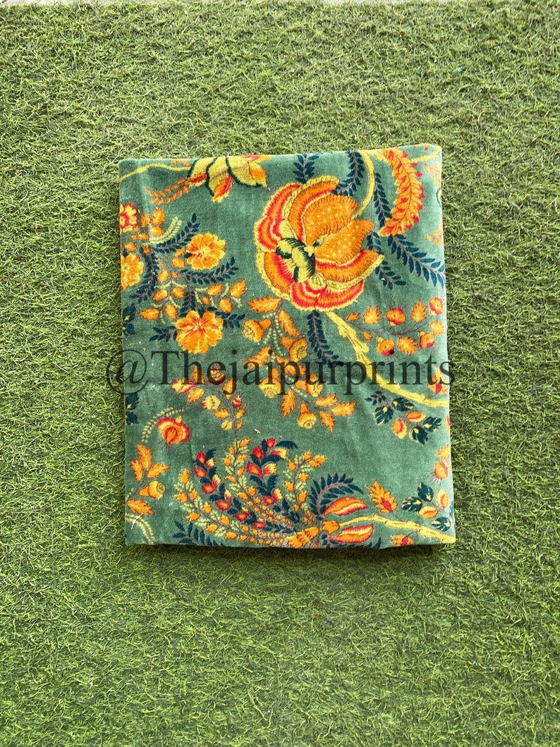 May include: A green fabric with a floral pattern in shades of yellow, orange, and red. The fabric has a vintage feel and is perfect for crafting projects.