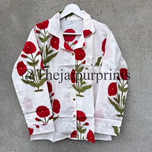 May include: White button-down pajama top with a red floral pattern and green leaves. The shirt has a pocket on the chest and is hanging on a white hanger. The text "Thejaipurprints" is visible.