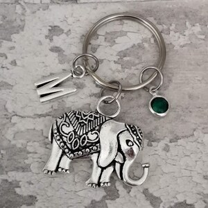 Pu&ograve; includere: Portachiavi con ciondolo in argento a forma di elefante dettagliato, ciondolo con gemma verde e ciondolo in argento con la lettera M.