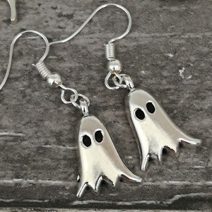 May include: A pair of silver ghost earrings. Each ghost has two black eyes.