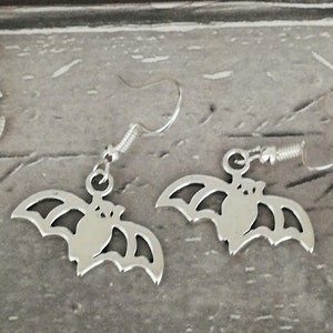 May include: A pair of silver earrings with a bat design. The bats are detailed with wings and a body.
