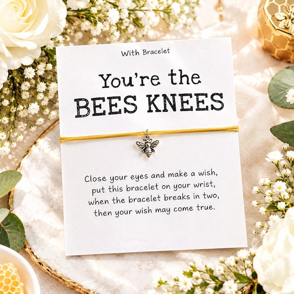 Könnte beinhalten: Ein gelbes Schnurarmband mit einem kleinen silbernen Bienenanhänger auf einer weißen Karte mit dem Text "With Bracelet", "You're the BEES KNEES" und einem Gedicht darüber, sich etwas zu wünschen, wenn das Armband entzwei bricht.