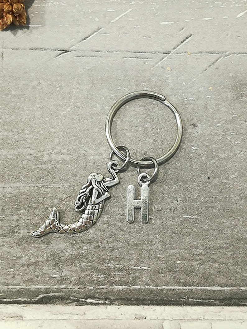 May include: Silver keychain with a mermaid charm and a letter H charm.