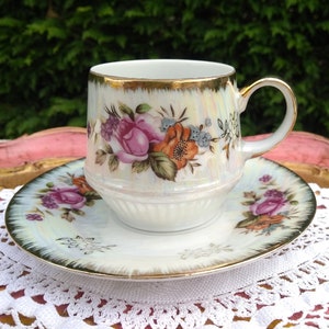 Preciosa taza de té y platillo de loza color crema decorados con rosas y flores.
