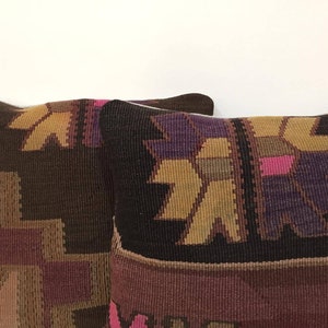 May include: Two brown, purple, and gold patterned throw pillows with a geometric design.