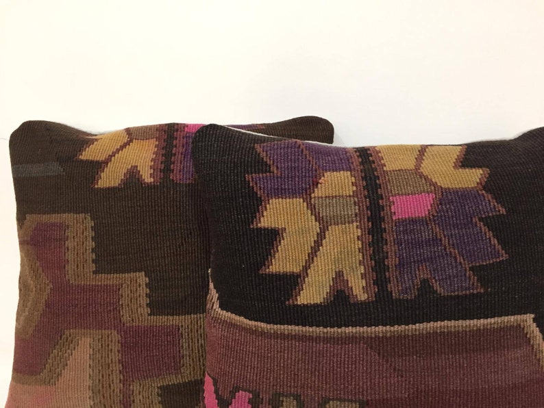 May include: Two brown, purple, and gold patterned throw pillows with a geometric design.