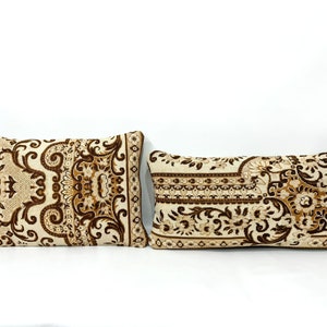 May include: Two decorative throw pillows with a brown and cream patterned design. The pillows feature a floral and paisley design.