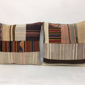 May include: Two square patchwork throw pillows with a variety of colorful stripes and patterns. The pillows are made of woven fabric and have a beige background.