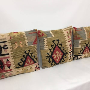 May include: Three decorative throw pillows with a traditional Turkish kilim pattern in shades of beige, brown, red, and black.