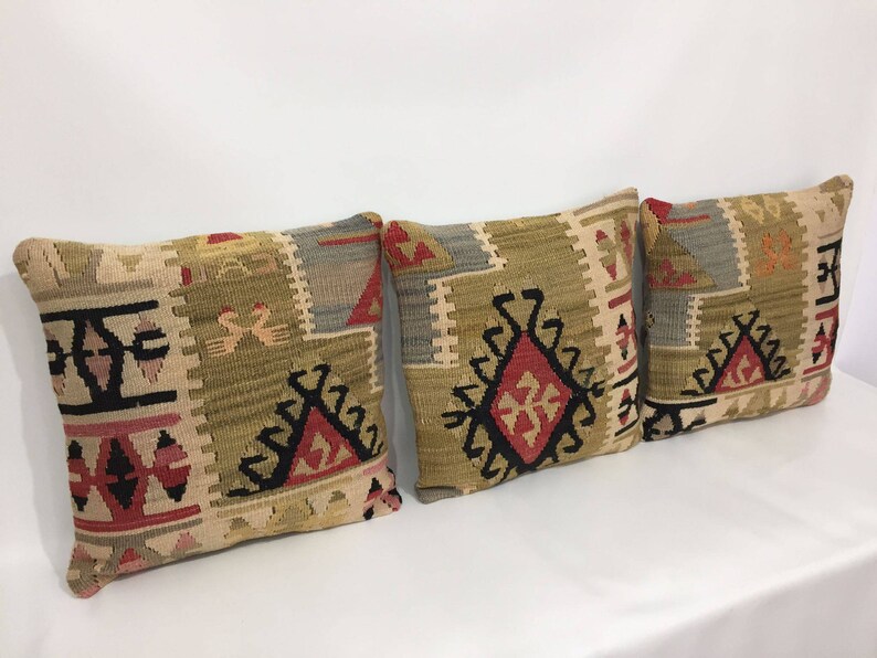 May include: Three decorative throw pillows with a traditional Turkish kilim pattern in shades of beige, brown, red, and black.