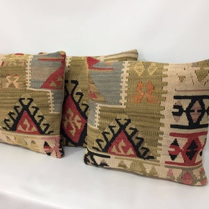 May include: Three decorative throw pillows with a geometric pattern in shades of beige, brown, red, and black.