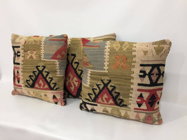 May include: Three decorative throw pillows with a geometric pattern in shades of beige, brown, red, and black.