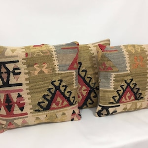 May include: Two decorative throw pillows with a geometric pattern in shades of beige, brown, red, and black. The pillows are made of woven fabric and have a traditional design.