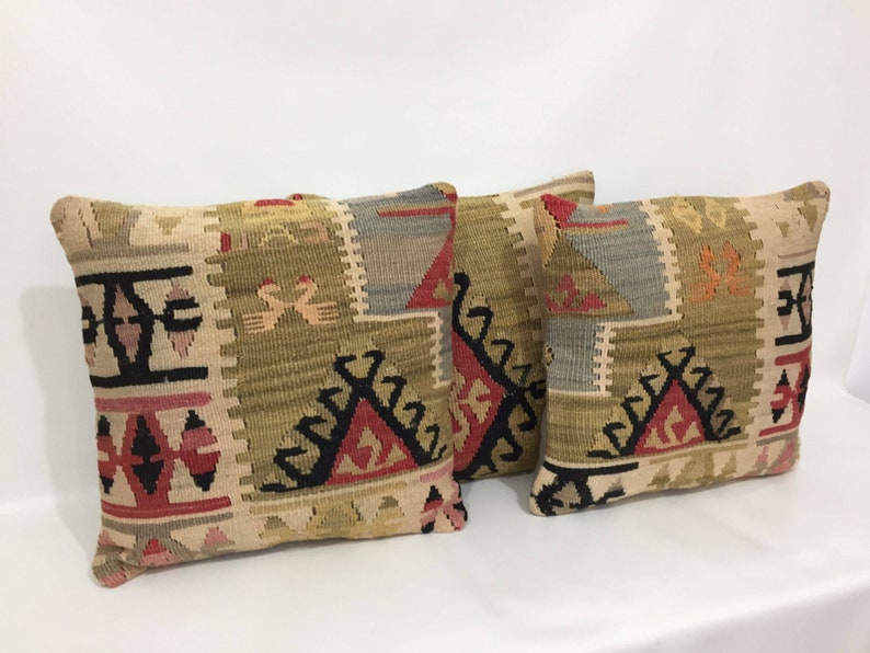 May include: Two decorative throw pillows with a geometric pattern in shades of beige, brown, red, and black. The pillows are made of woven fabric and have a traditional design.