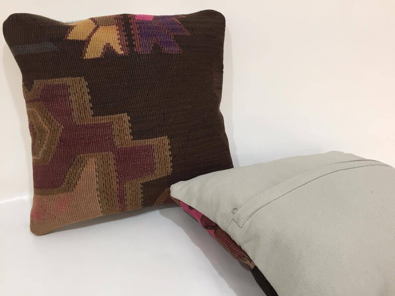May include: Two decorative throw pillows, one with a brown background and a colorful geometric pattern, and the other with a plain light gray fabric.