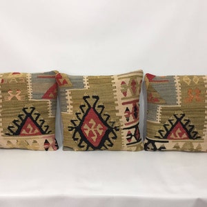 May include: Three decorative throw pillows with a traditional geometric pattern in shades of beige, brown, red, and black.