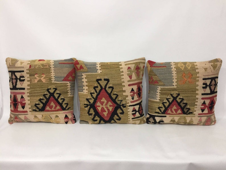 May include: Three decorative throw pillows with a traditional geometric pattern in shades of beige, brown, red, and black.