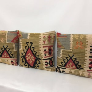 May include: Three decorative throw pillows with a geometric pattern in shades of beige, brown, red, and black.