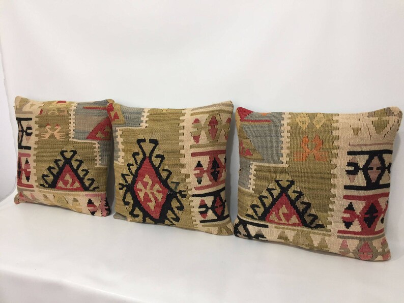 May include: Three decorative throw pillows with a geometric pattern in shades of beige, brown, red, and black.