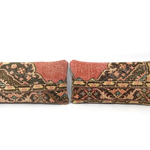 May include: Two rectangular throw pillows featuring a vintage-style woven pattern in shades of terracotta, dark brown, and muted teal. The design displays intricate geometric and floral motifs with a prominent border and a weathered, textured appearance.