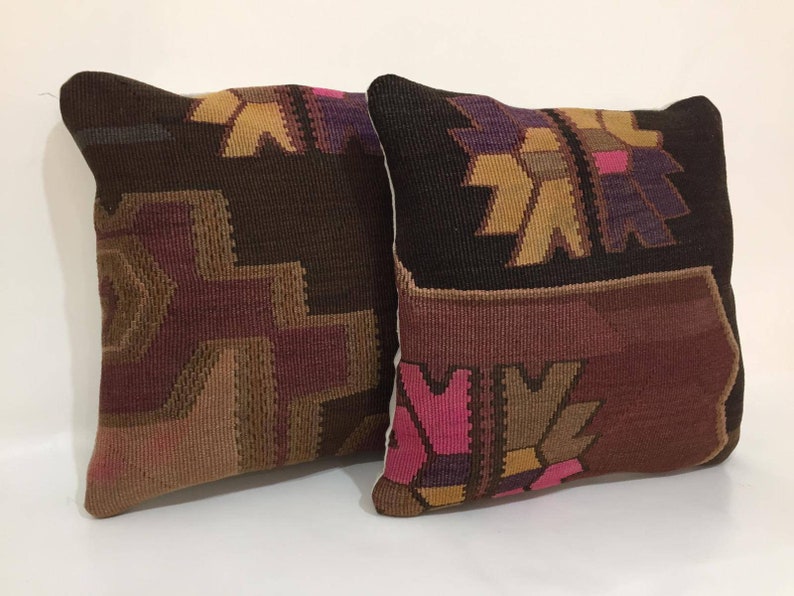 May include: Two decorative throw pillows with a woven pattern in shades of brown, pink, and purple. The pillows have a geometric design with a traditional look.