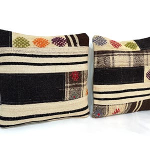 May include: Two decorative throw pillows with a patchwork design. The pillows are made of a beige and brown fabric with colourful embroidered details.