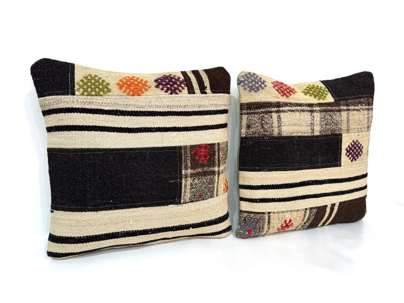 May include: Two decorative throw pillows with a patchwork design. The pillows are made of a beige and brown fabric with colourful embroidered details.