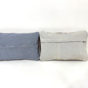 Puede incluir: Dos cojines rectangulares colocados uno al lado del otro. El coj&iacute;n de la izquierda es de un color azul pizarra s&oacute;lido con una costura horizontal visible en el centro. El coj&iacute;n de la derecha es de color beige claro o blanco roto con una costura.