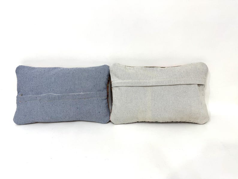 Puede incluir: Dos cojines rectangulares colocados uno al lado del otro. El coj&iacute;n de la izquierda es de un color azul pizarra s&oacute;lido con una costura horizontal visible en el centro. El coj&iacute;n de la derecha es de color beige claro o blanco roto con una costura.